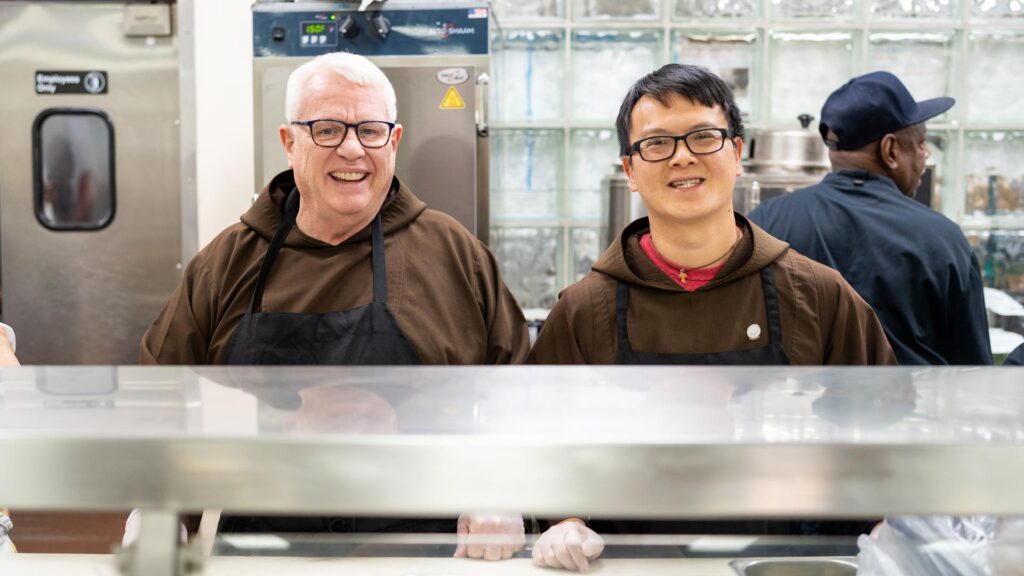 Br. Gary Wegner and Br. Tien Dinh smile while serving at the Meldrum Community Center.