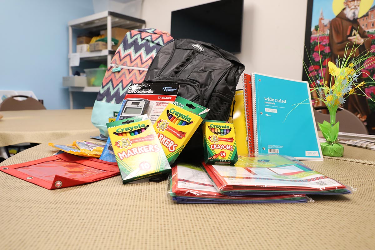 School supplies, including crayons, notebooks and other items, sit on a table.